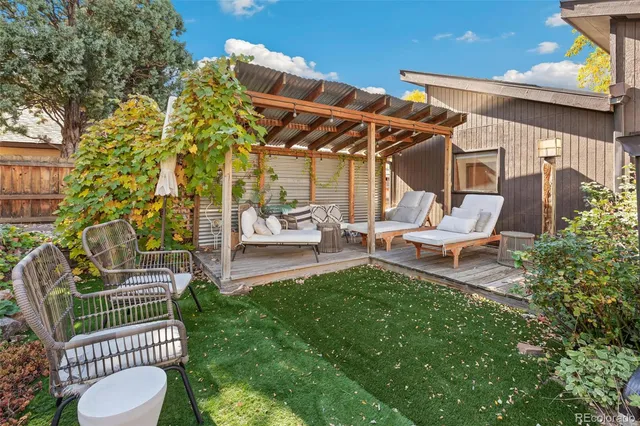 a view of a patio with couches potted plants and a large tree