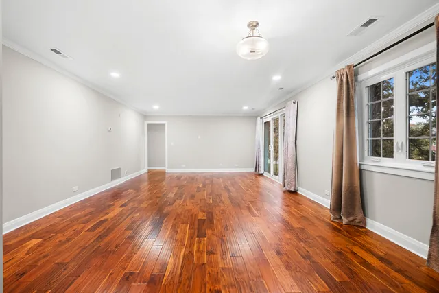 a view of empty room with wooden floor and fan