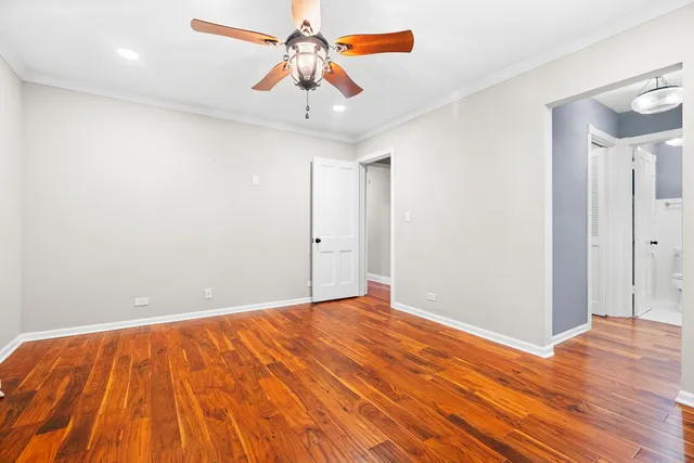an empty room with wooden floor and a chandelier fan