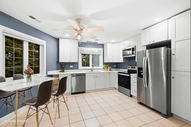 a kitchen with a refrigerator a counter space dining table and chairs
