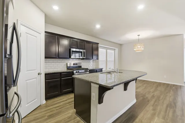 a kitchen with stainless steel appliances granite countertop a sink stove microwave and refrigerator