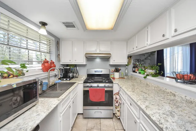 a kitchen with stainless steel appliances granite countertop a stove a sink and a microwave