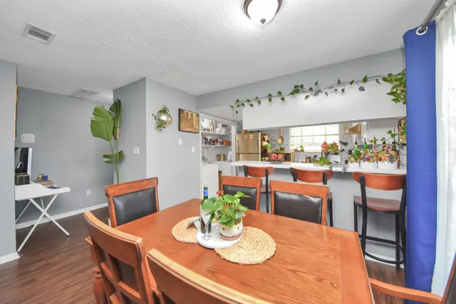 a view of a dining room with furniture a kitchen and wooden floor