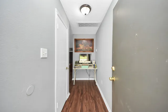a view of a hallway with wooden floor and a bathroom