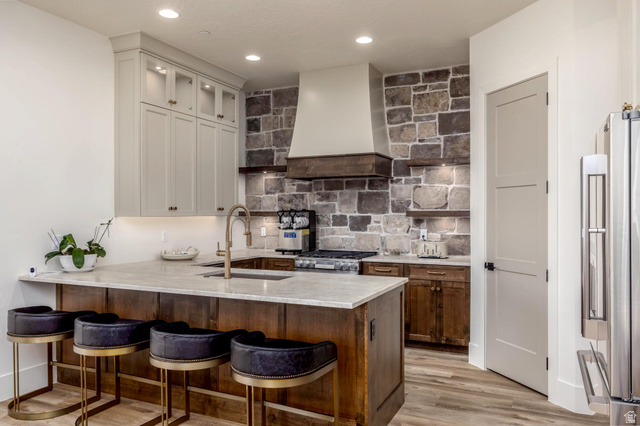 168 South Rancho Santa Fe Virgin, UT 84779 - Photo 30 of 68 Casita Kitchen with stone accent wall, wood-finish flooring, light-toned upper cabinetry with glass inserts, wood-paneled island, and integrated range hood