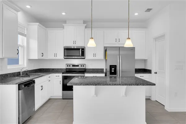 a kitchen with stainless steel appliances granite countertop a sink a stove a refrigerator a center island and cabinets