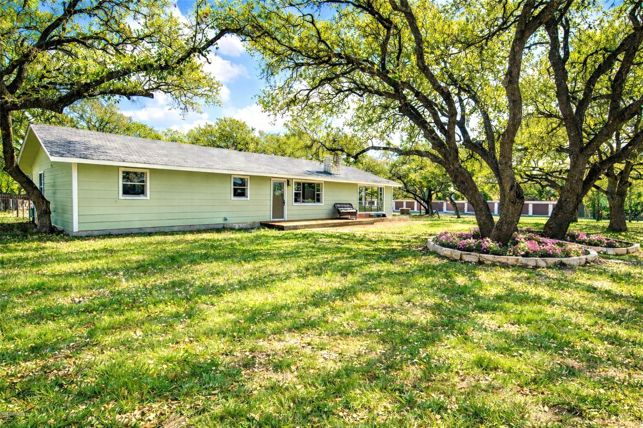 207 Haley Road Johnson City, TX 78636 - Photo 30 of 31 A verdant lawn embraces this charming ranch-style dwelling, shaded by mature, broad-canopied trees.