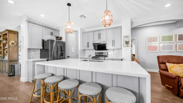 a kitchen with stainless steel appliances kitchen island granite countertop a dining table chairs and refrigerator