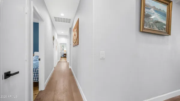 a view of a hallway with wooden floor and a bathroom