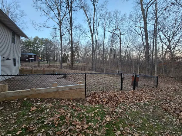 a view of a backyard with table and chairs with wooden fence and trees
