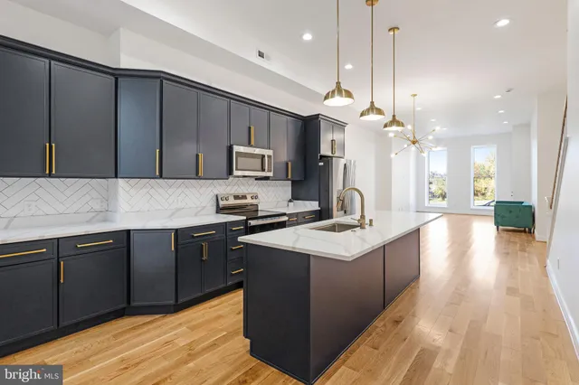 a kitchen with a sink a center island a stove cabinets and wooden floor
