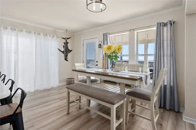 a kitchen with stainless steel appliances a dining table chairs in it and wooden floors