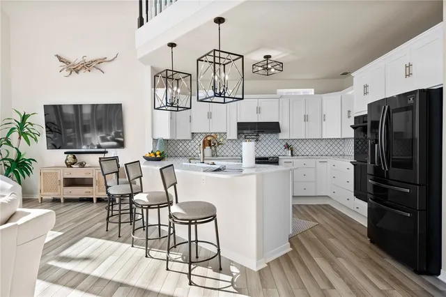 a kitchen with stainless steel appliances a stove a refrigerator a sink dishwasher a dining table and chairs with wooden floor