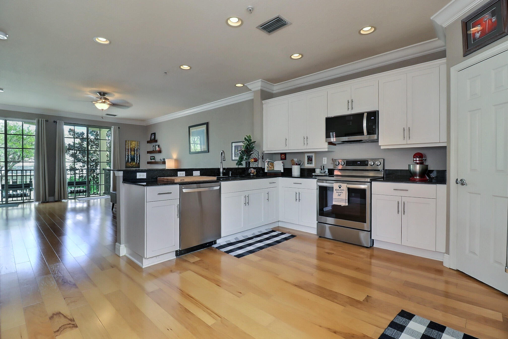 216 Quarry Knoll Way Jupiter, FL 33458 - Photo 7 of 23 a kitchen with stainless steel appliances granite countertop a refrigerator a stove top oven a sink a dining table and chairs with wooden floor