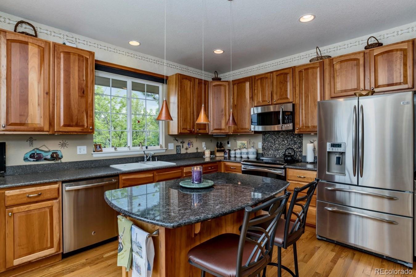 8974 Old Tom Morris Circle Highlands Ranch, CO 80129 - Photo 8 of 28 a kitchen with stainless steel appliances granite countertop a stove a refrigerator a sink dishwasher a dining table and chairs with wooden floor