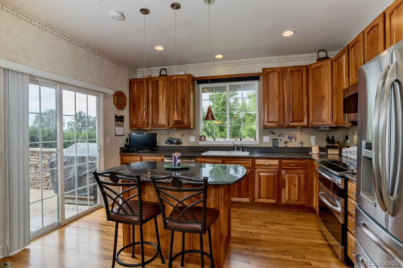 8974 Old Tom Morris Circle Highlands Ranch, CO 80129 - Photo 10 of 28 a kitchen with stainless steel appliances granite countertop a stove top oven a sink dishwasher a dining table and chairs with wooden floor