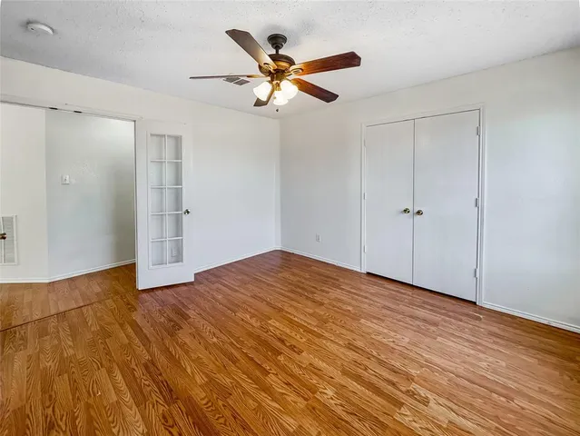 a view of empty room with wooden floor and ceiling fan