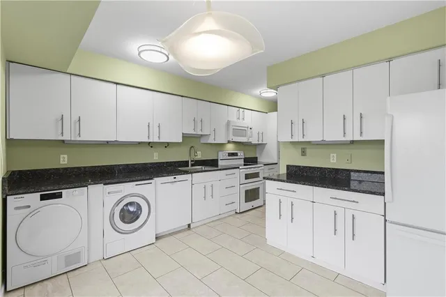 a kitchen with granite countertop white cabinets and white appliances