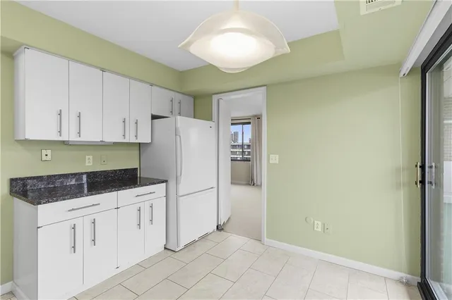 a kitchen with white cabinets and refrigerator