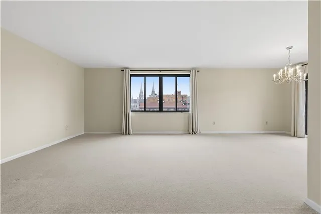 an empty room with chandelier fan and windows