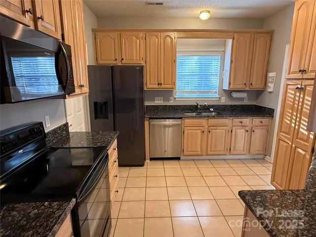 a kitchen with granite countertop a stove a sink and a refrigerator