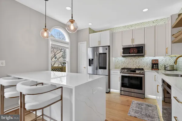 a kitchen with stainless steel appliances granite countertop a stove a refrigerator a kitchen island a sink cabinets and a dining table