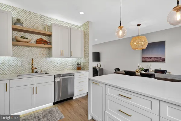 a kitchen with a sink dishwasher and white cabinets with wooden floor