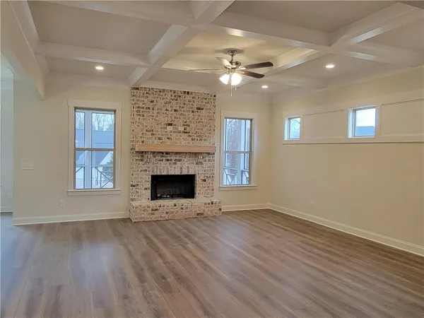 a view of an empty room with wooden floor fireplace and a window