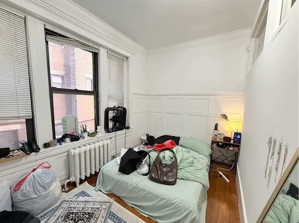 a bedroom with a bed and a dresser next to a window
