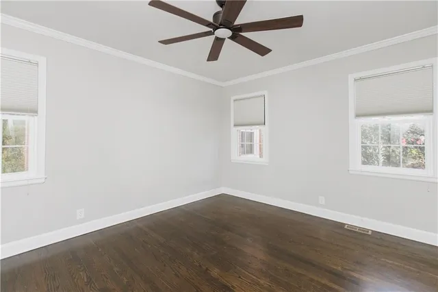 an empty room with wooden floor ceiling fan and windows