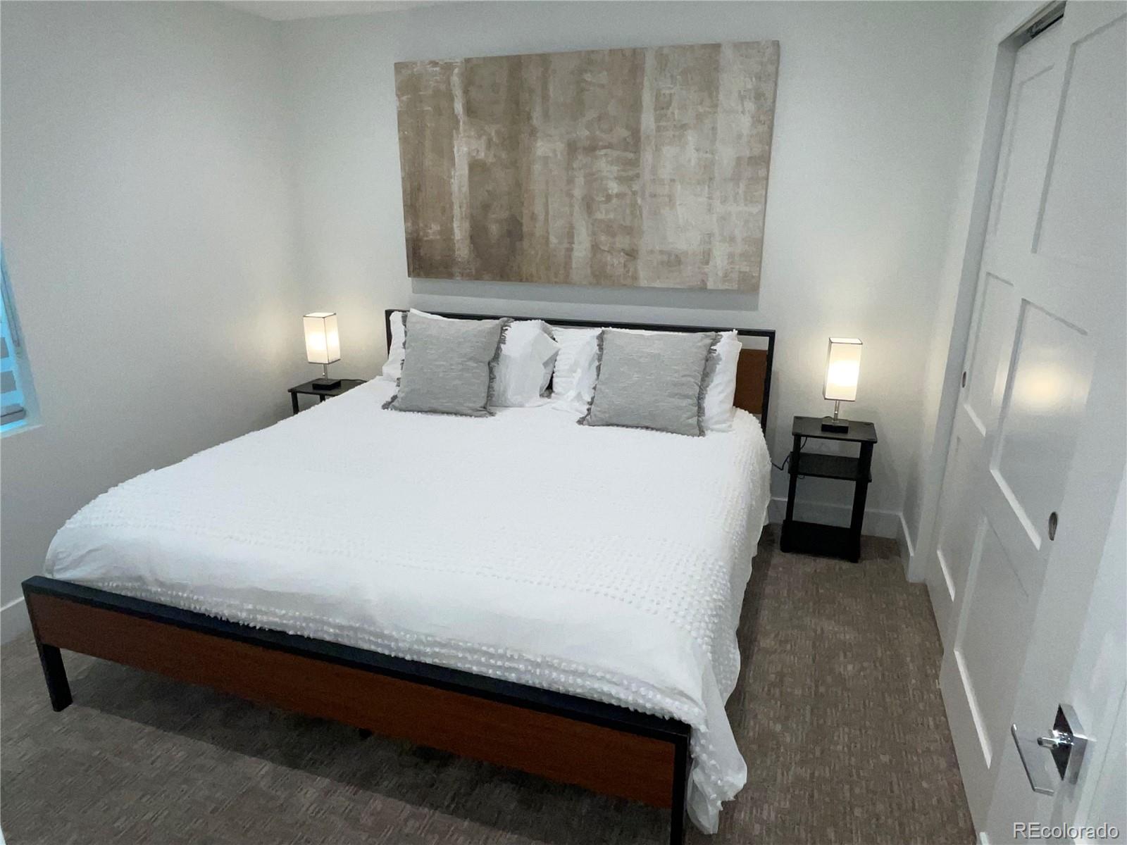 1310 Zenobia Street Denver, CO 80204 - Photo 9 of 9 a large bed sitting in a bedroom next to a lamp