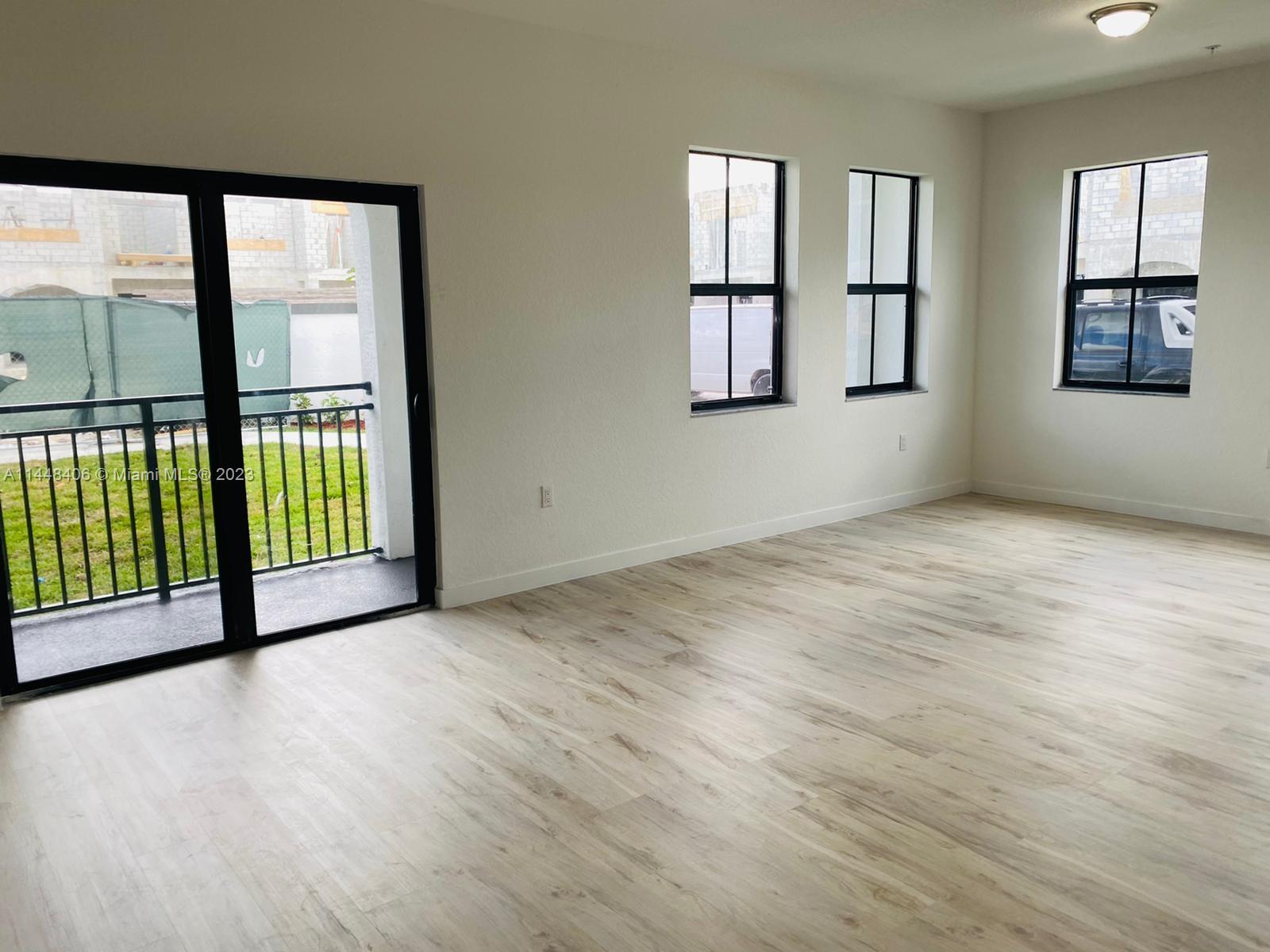 15520 Southwest 136th Street, Unit 106 Miami, FL 33196 - Photo 3 of 11 a view of an empty room with a window and wooden floor