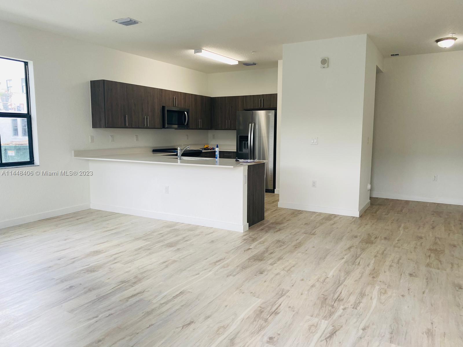 15520 Southwest 136th Street, Unit 106 Miami, FL 33196 - Photo 4 of 11 a kitchen with stainless steel appliances a refrigerator and a stove top oven