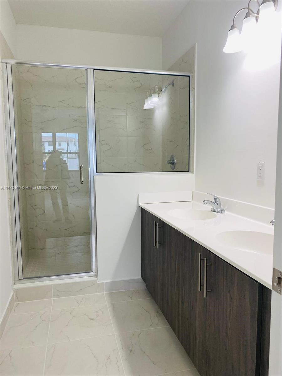 15520 Southwest 136th Street, Unit 106 Miami, FL 33196 - Photo 7 of 11 a bathroom with a double vanity sink mirror and shower