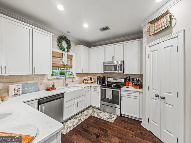 a kitchen with stainless steel appliances granite countertop a dining table chairs refrigerator and cabinets