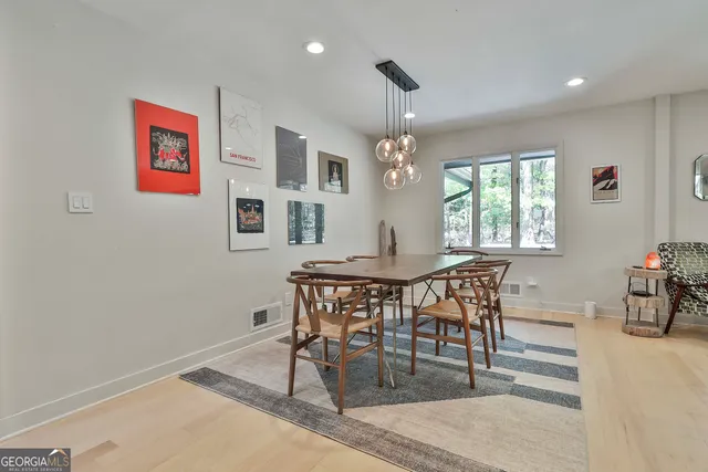 a dining room with wooden floor a chandelier a wooden table and chairs