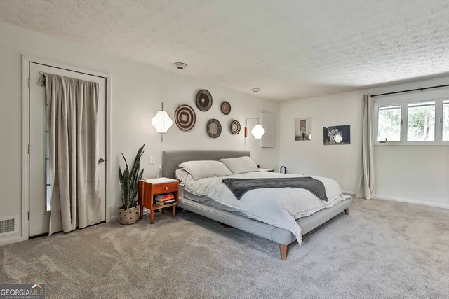 a spacious bedroom with a bed and dresser with mirror