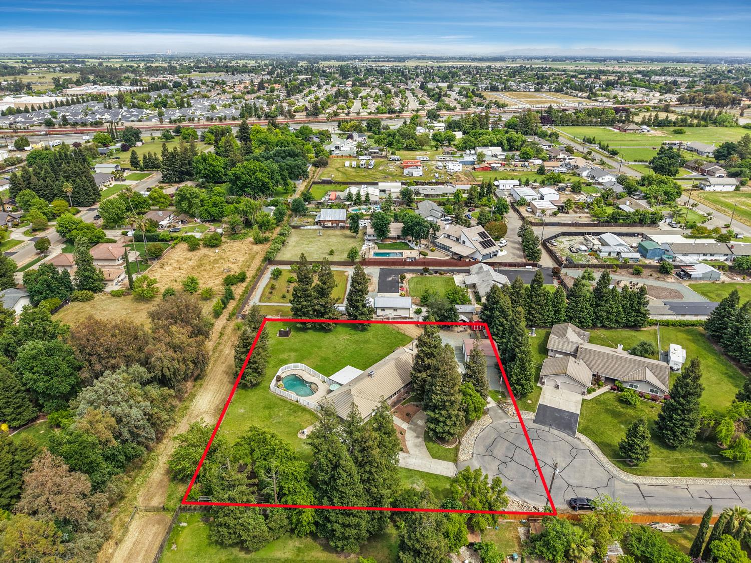 an aerial view of residential houses with outdoor space and trees