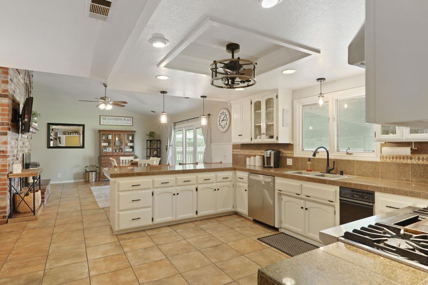 12963 Spring Time Lane Galt, CA 95632 - Photo 19 of 49 a large kitchen with stainless steel appliances a stove a sink a dining table and chairs with wooden floor