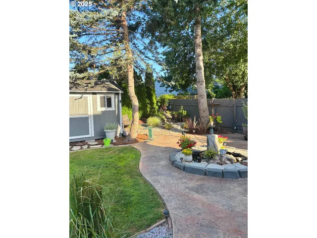 a view of a backyard with table and chairs potted plants and large tree