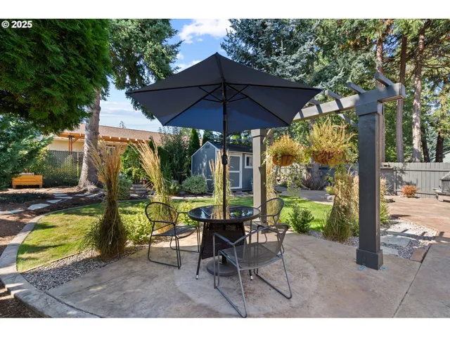 a view of a patio with table and chairs under an umbrella with a small yard