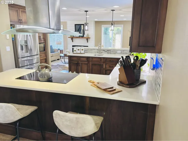 a kitchen with stainless steel appliances granite countertop a table chairs in it and wooden floors