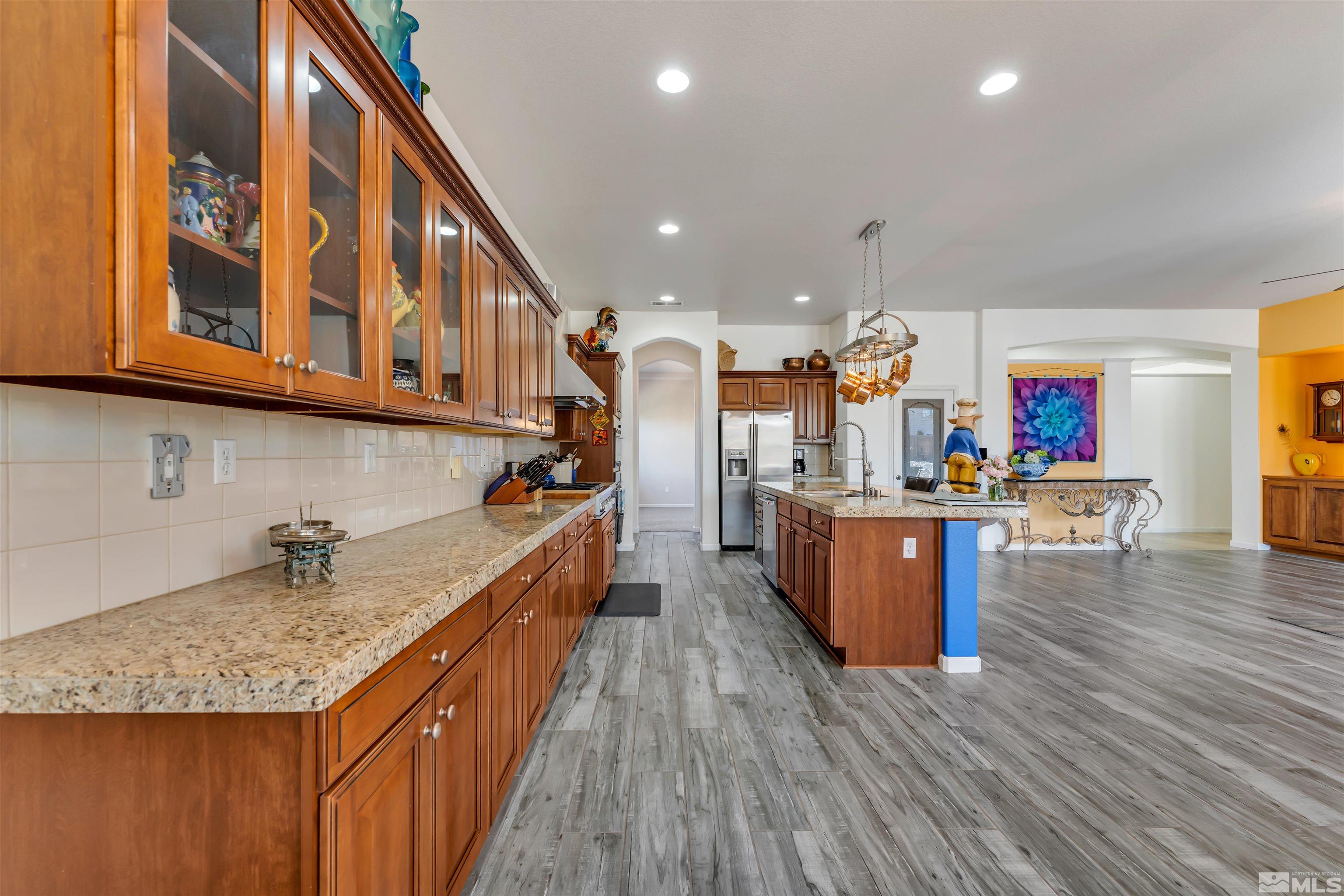 10555 Dillingham Drive Reno, NV 89521 - Photo 20 of 34 a kitchen with kitchen island granite countertop wooden floors and a view of living room