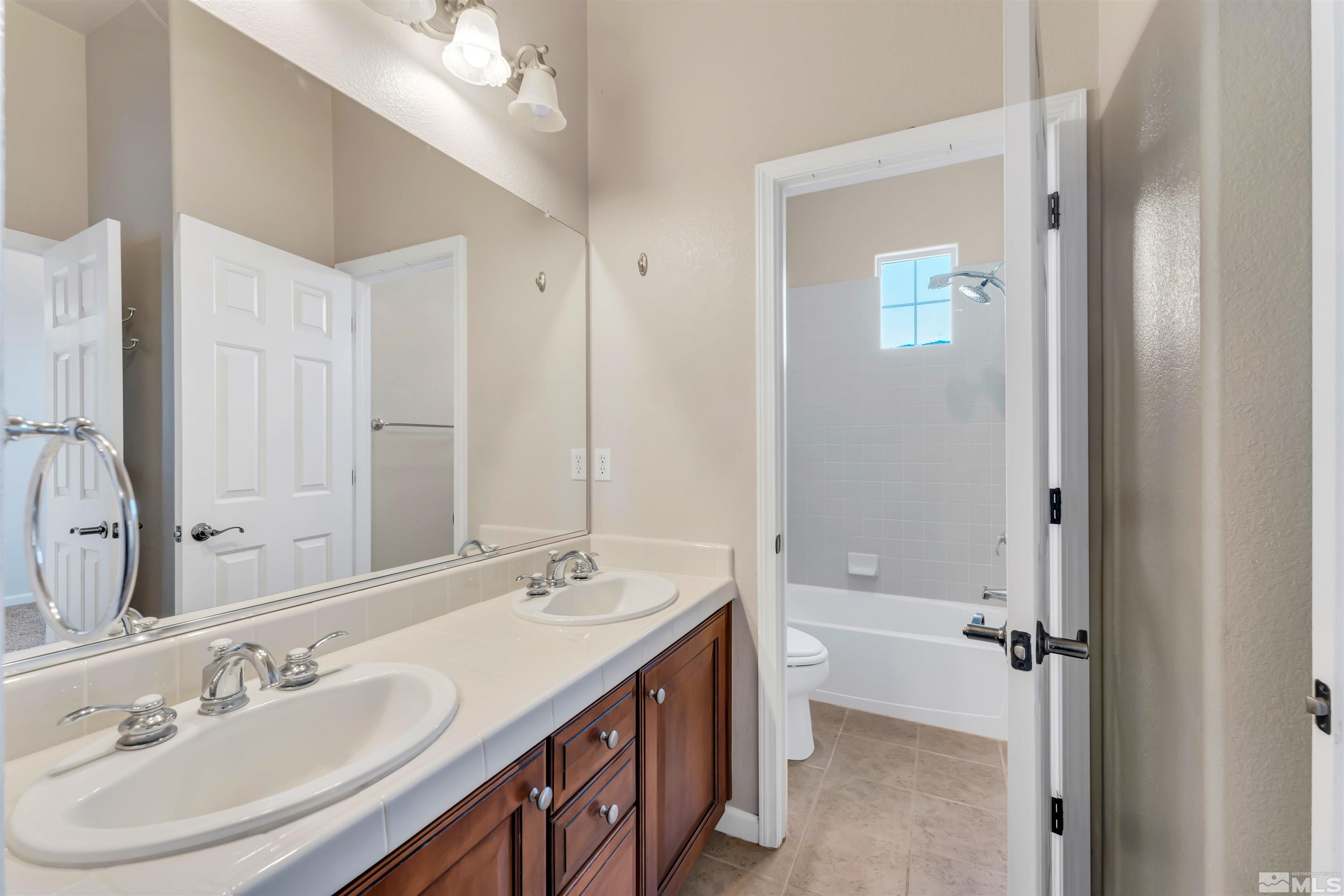 10555 Dillingham Drive Reno, NV 89521 - Photo 8 of 34 a bathroom with a granite countertop double vanity sink a mirror and a bathtub