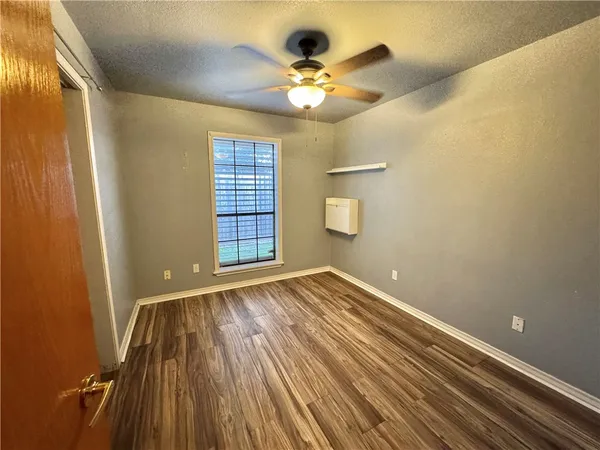 a view of an empty room with a window and wooden floor