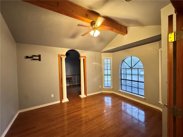 a view of an empty room with window and wooden floor