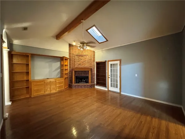 an empty room with wooden floor fire place and windows