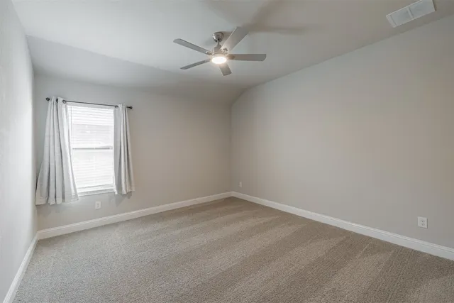 an empty room with chandelier fan and windows