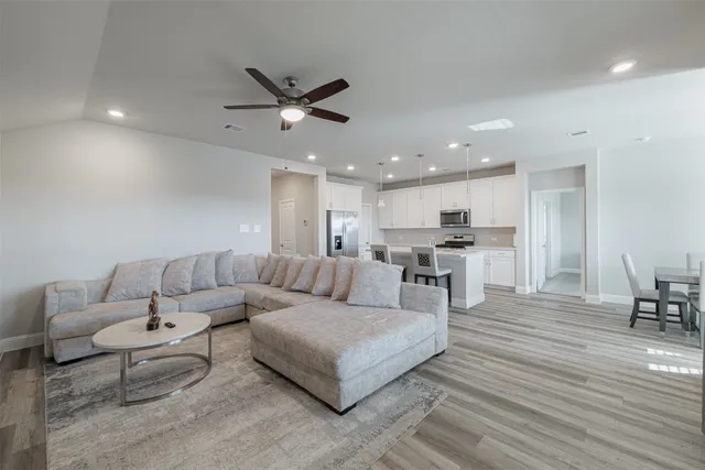 a living room with furniture and kitchen view with wooden floor