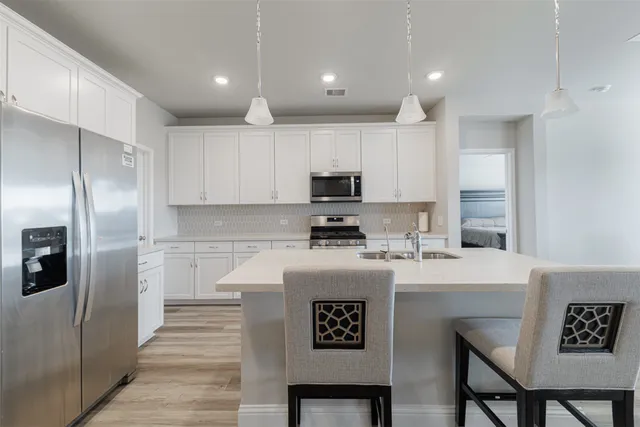 a kitchen with granite countertop a refrigerator stove microwave and cabinets
